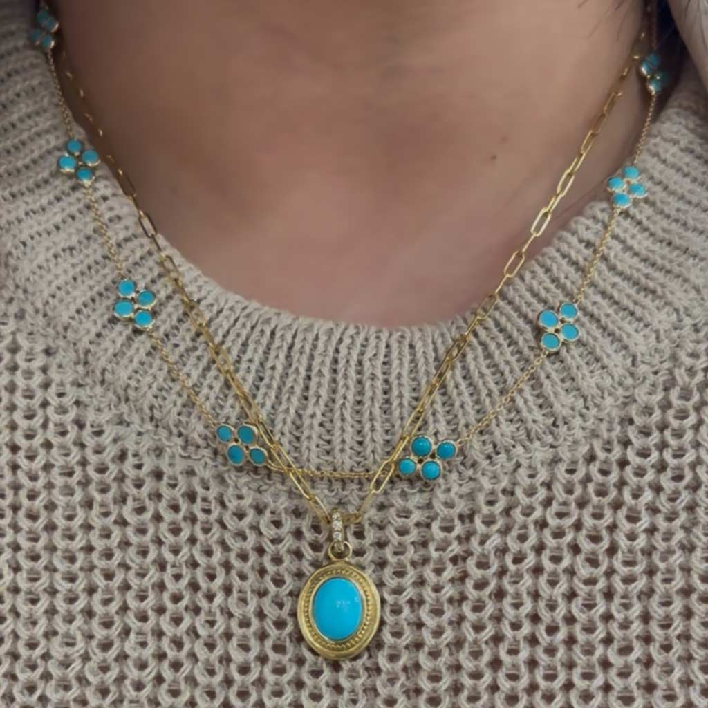 Gold necklace with turquoise stones on a textured beige sweater